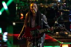Man holding red electric guitar while singing into a mic