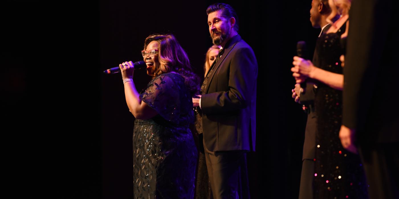 group of singers performing on stage, one singer performers in the forefront