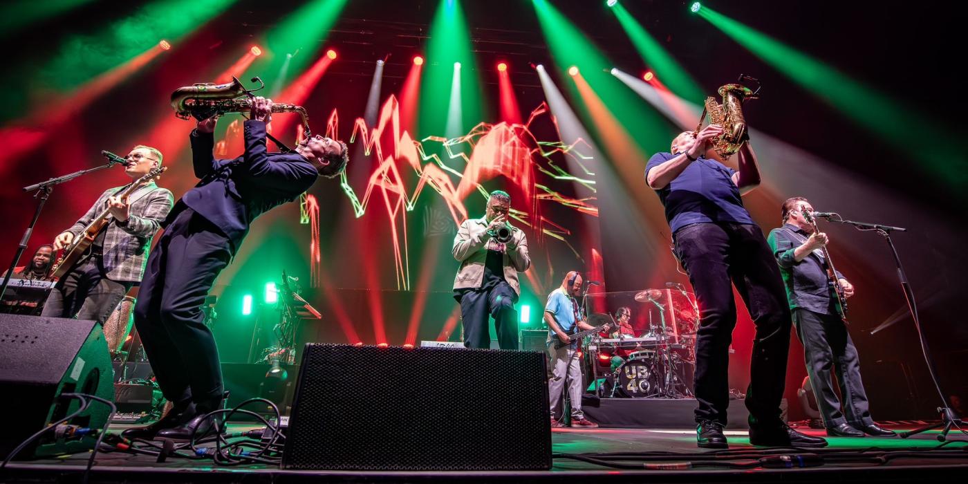singer and two saxophonists on stage with green and red stage lights