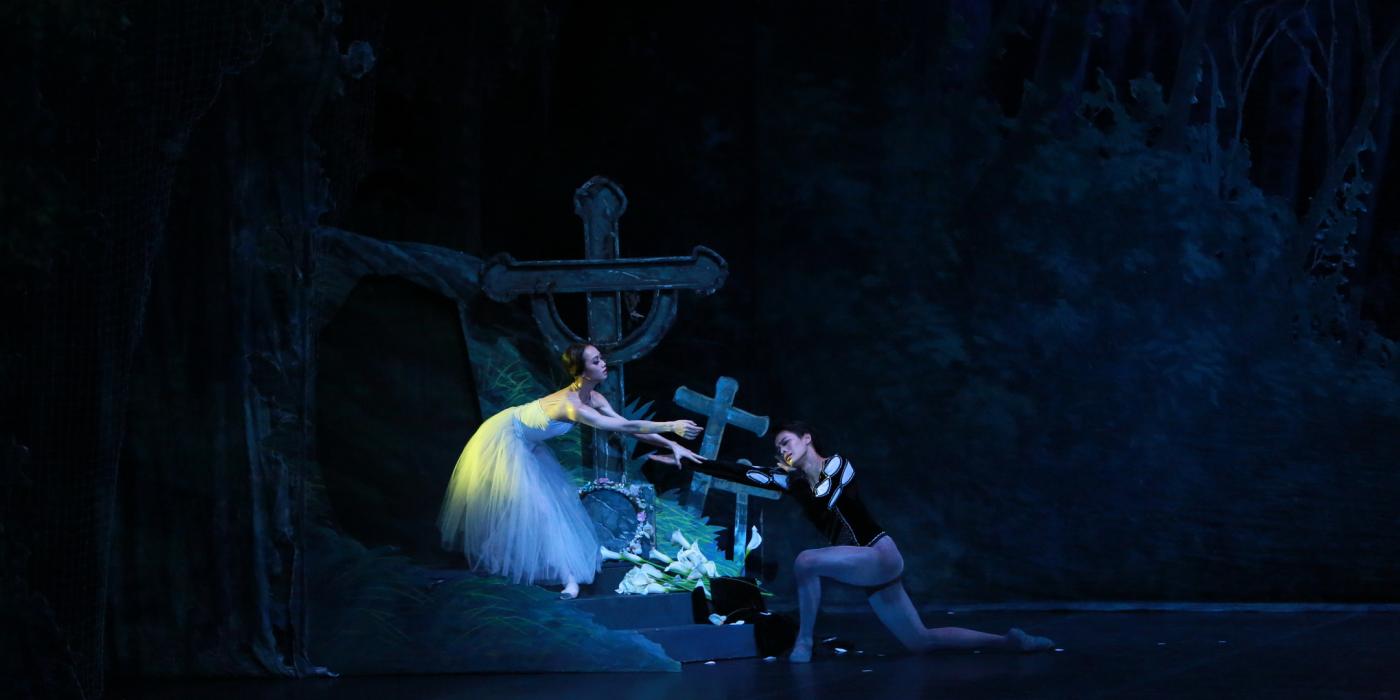 Woman and man hovering over crosses reaching for one another in ballet. 