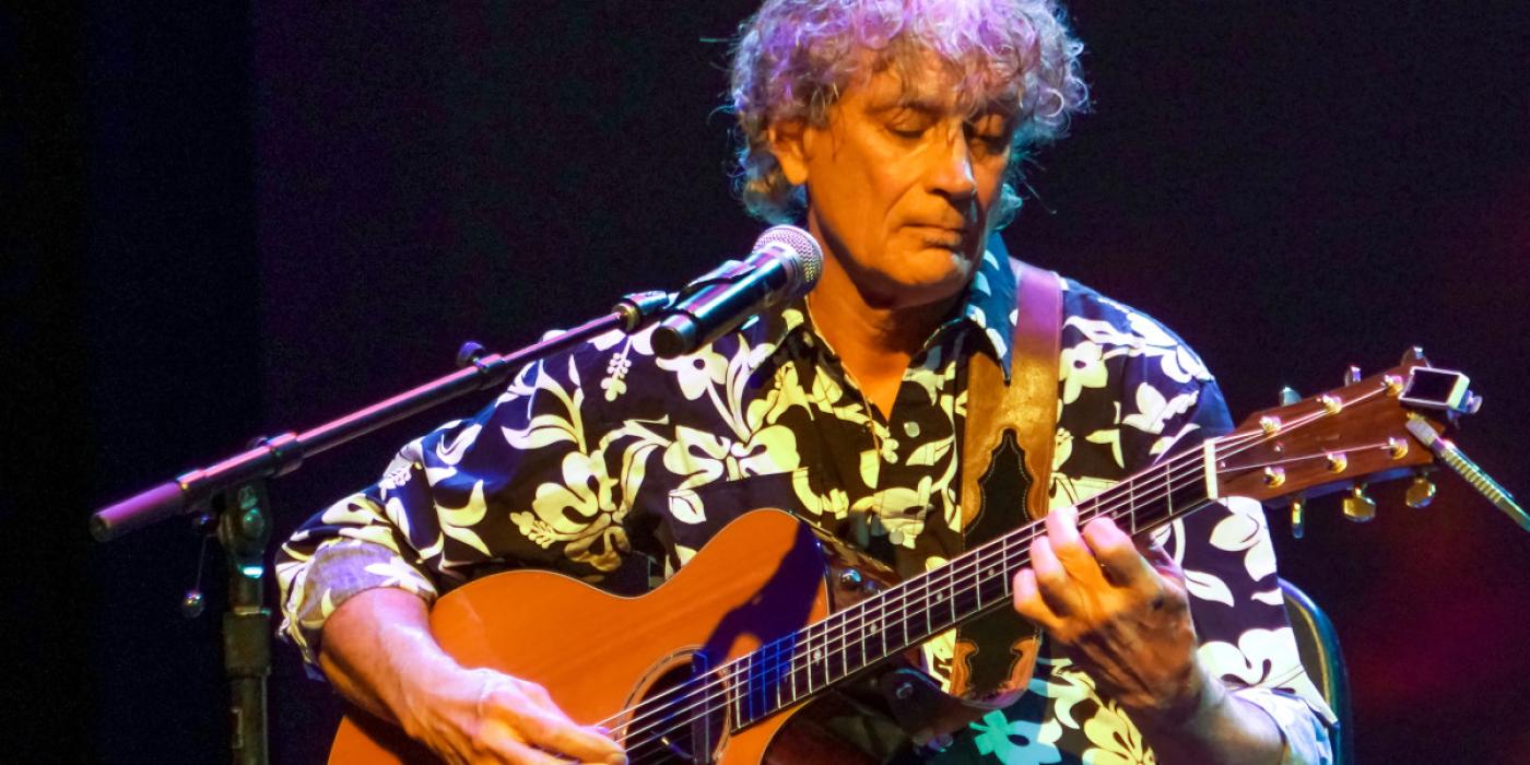 Caucasian Male holding a guitar.