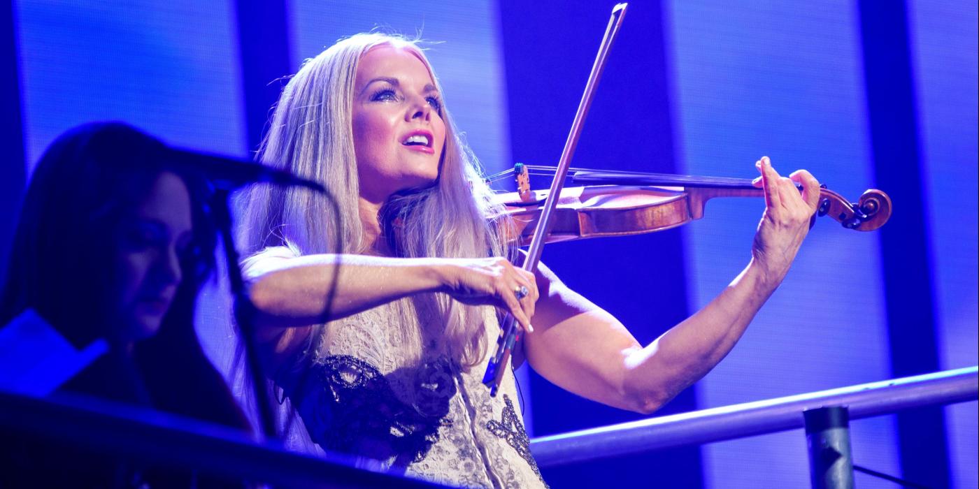 Woman on stage playing violin with blue lit background