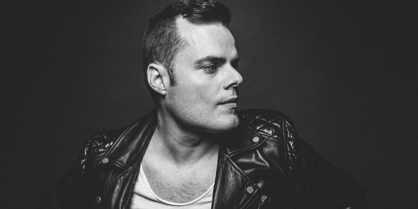 Black and white image of a caucasian male wearing a black leather jacket with white under-shirt.