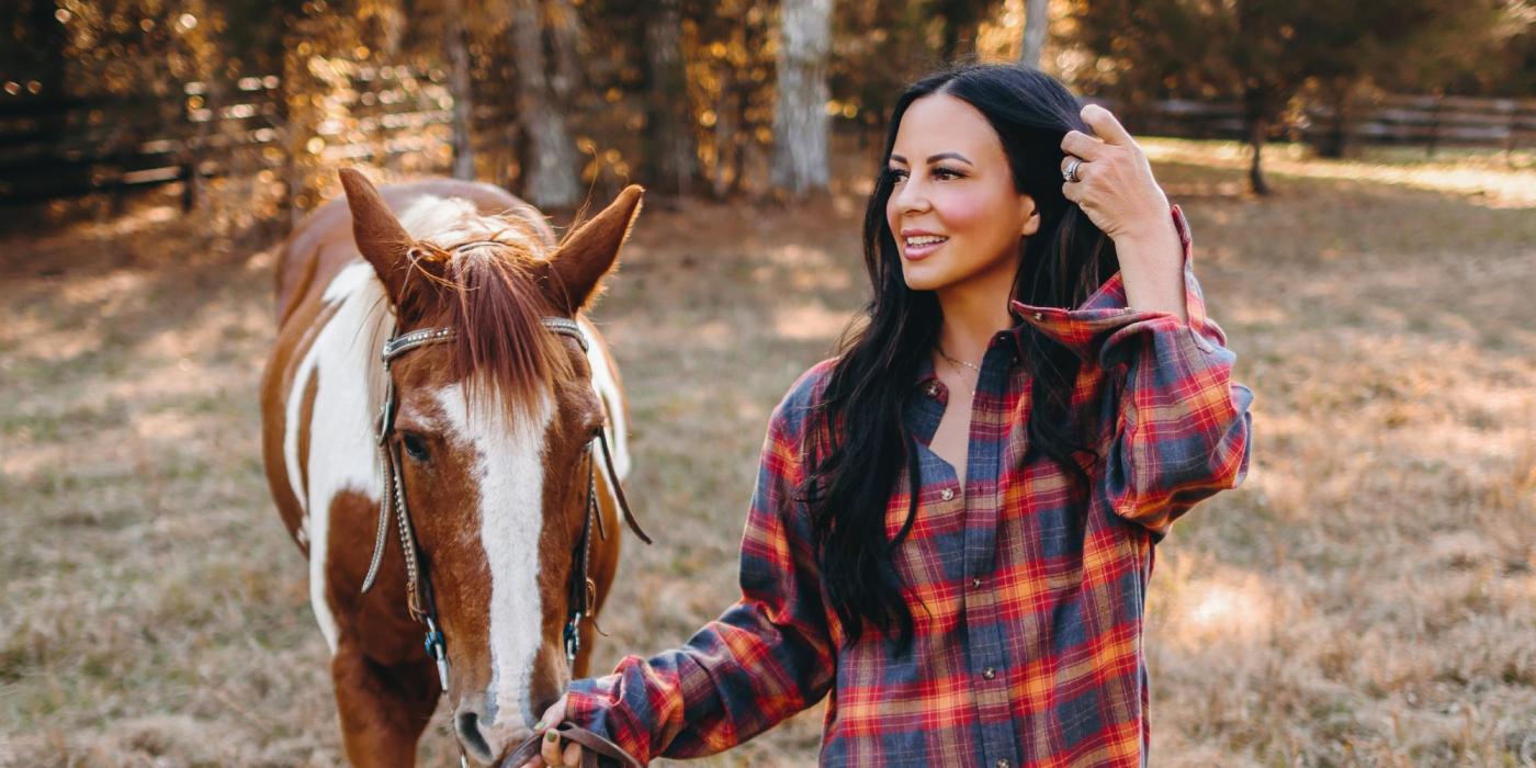 Sara Evans walking a horse outside