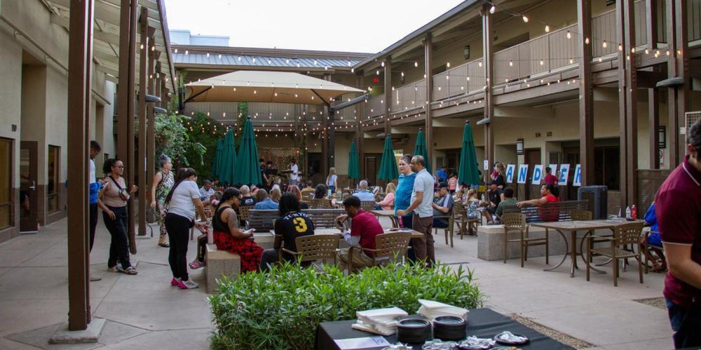 People gathered in courtyard with fairy lights and food