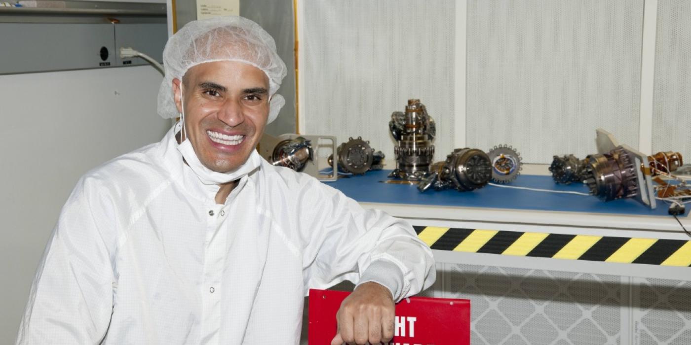 Kobie Boykins dressed in white smiling in front of rover wheels