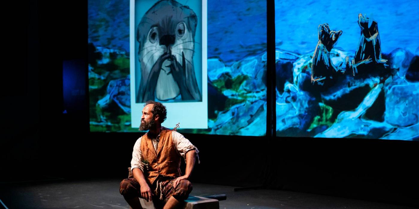 Man sitting on stage with a photo of otter on a projected screen