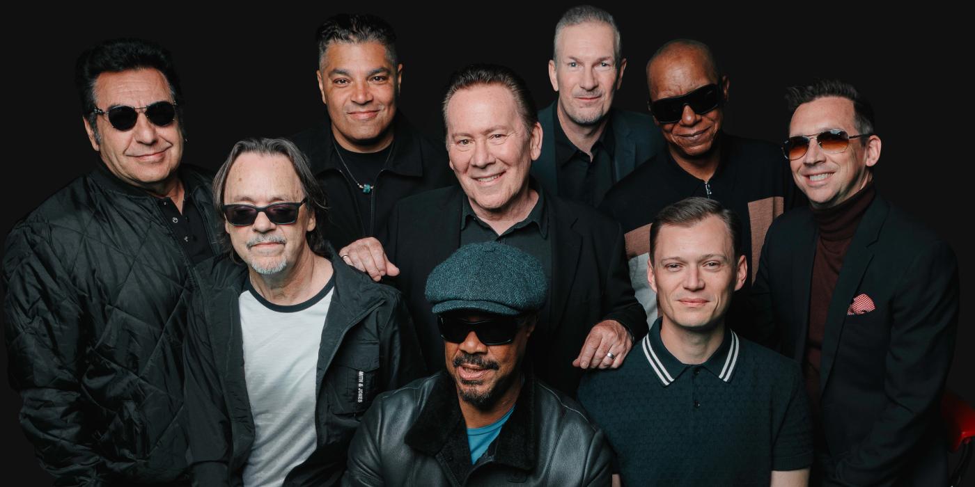 Group of 9 men dressed in black and gray attire with a black background