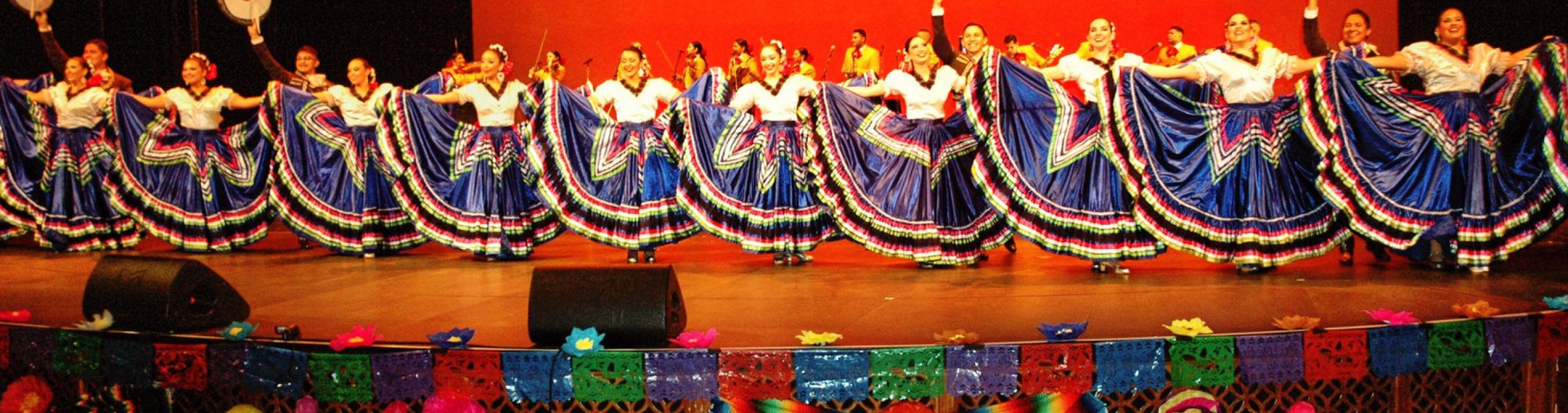 A line of Ballet Folklorico dancers in blue skirts with colorful trim.