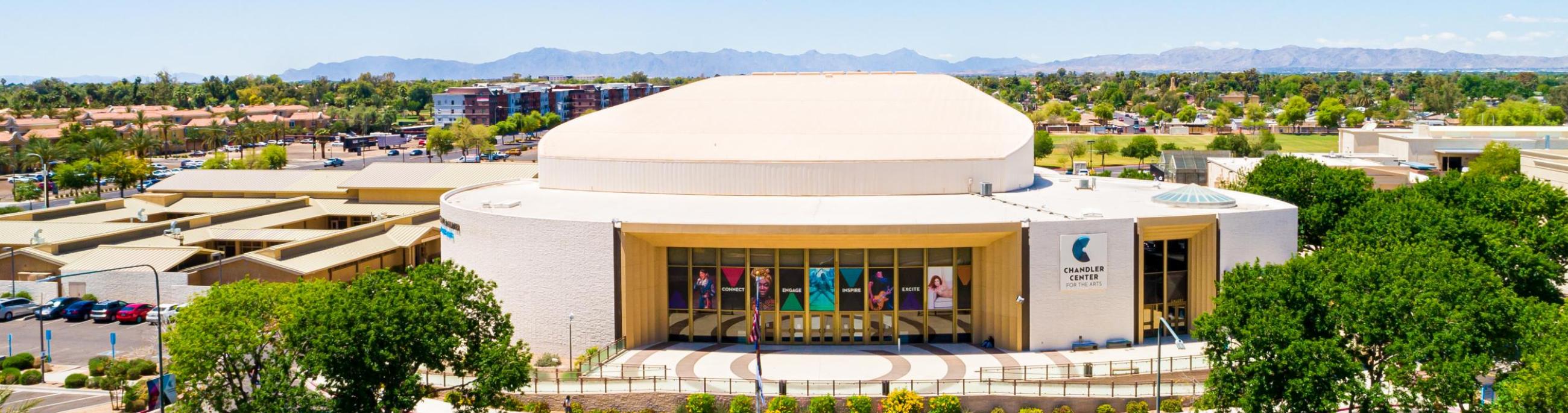 The CCA performing arts building with trees on either side, grass in front and a blue sky above. 