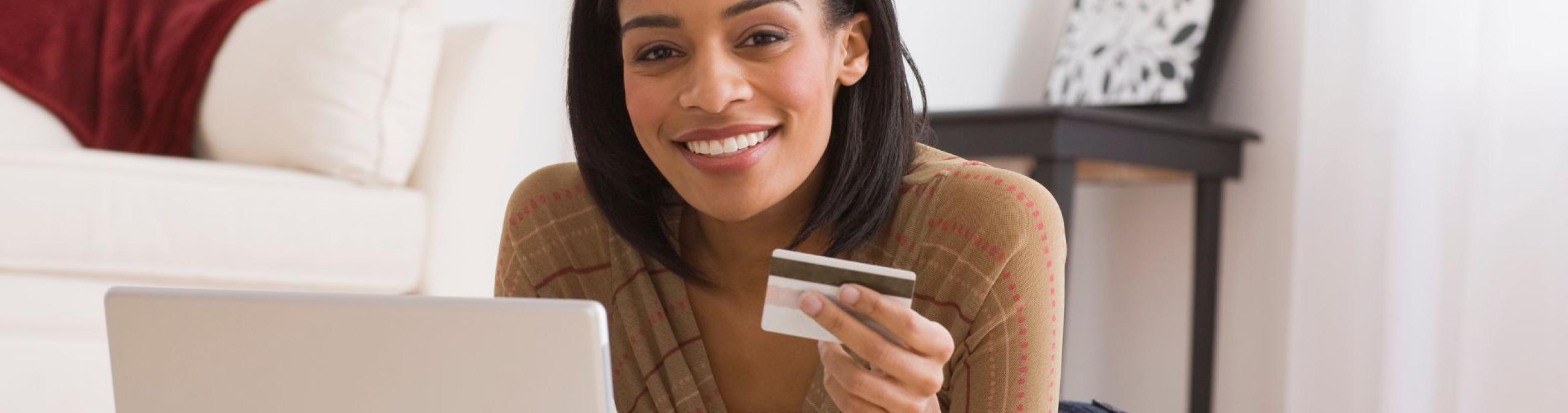 black woman with credit card looking at the computer smiling