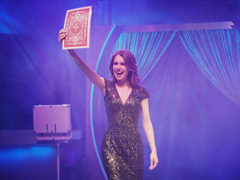 Woman excitedly holding out large playing card