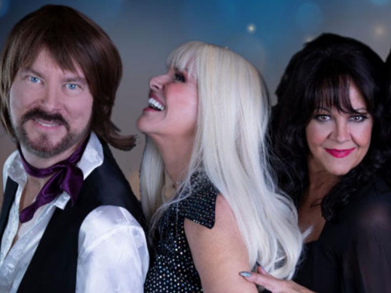 4 performers dressed in disco attire 