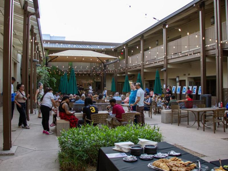 People gathered in courtyard with fairy lights and food