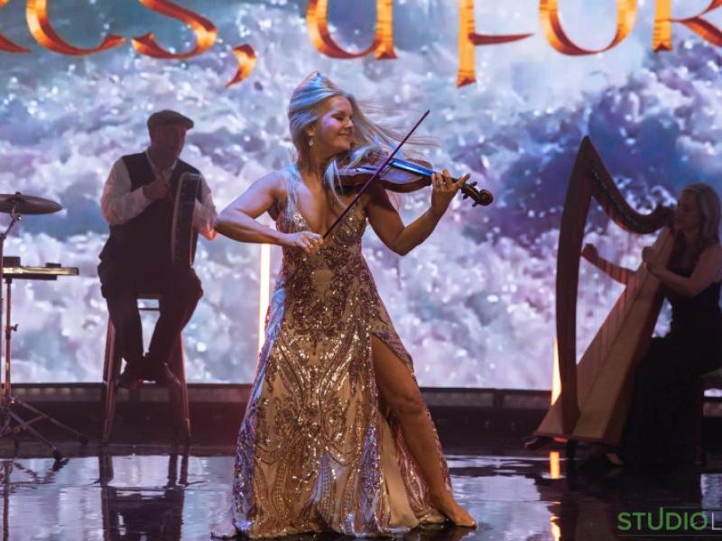 Celtic Spells on stage performing on fiddle wearing a golden dress
