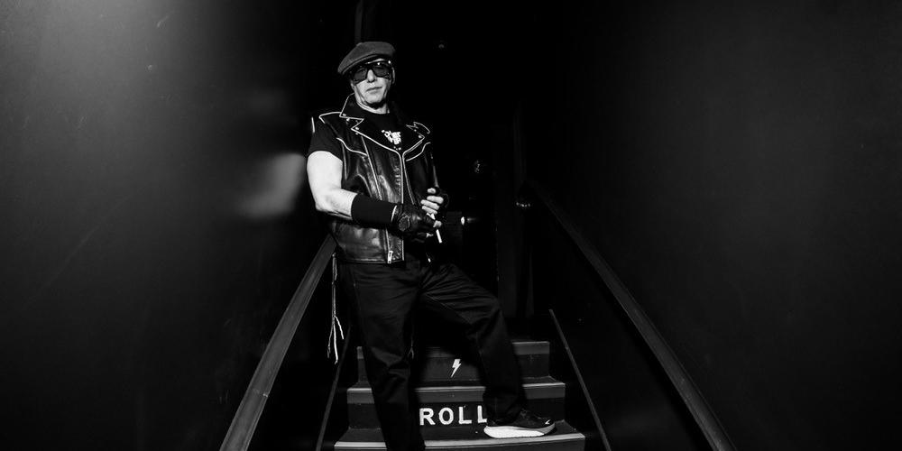 Andrew Dice Clay stands on a dark stairwell