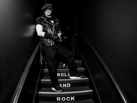 Andrew Dice Clay stands on a dark stairwell