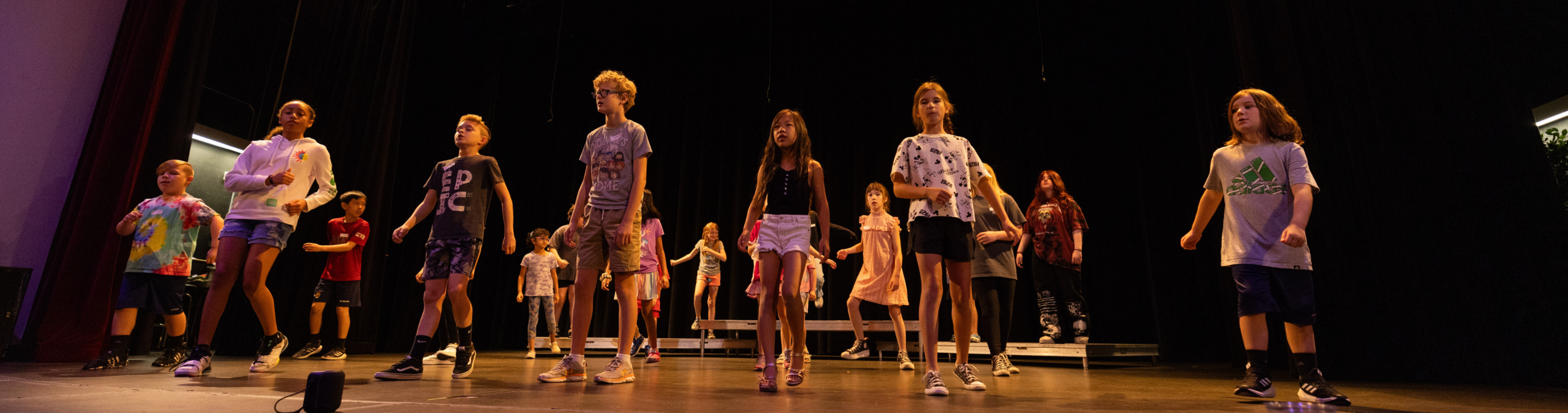 children standing on top of a stage practicing for a performance