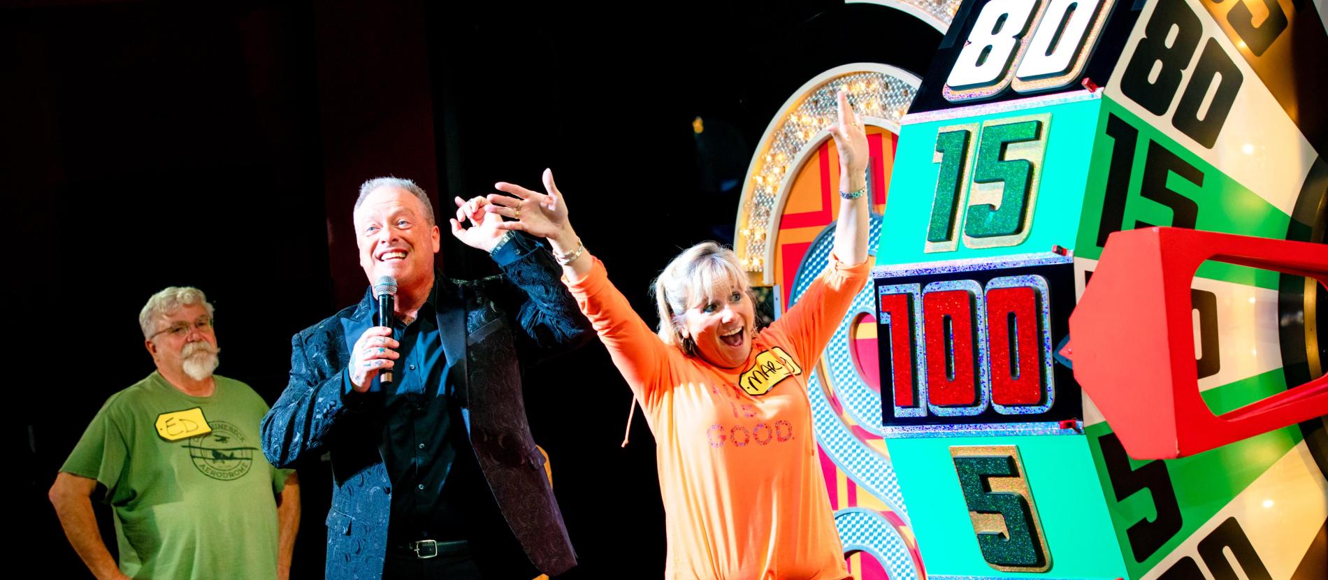 excited woman with her arms up looking at The Price is Right wheel 