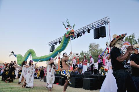 masked dancers leading a procession with feathered serpent puppet