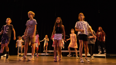 children standing on top of a stage practicing for a performance