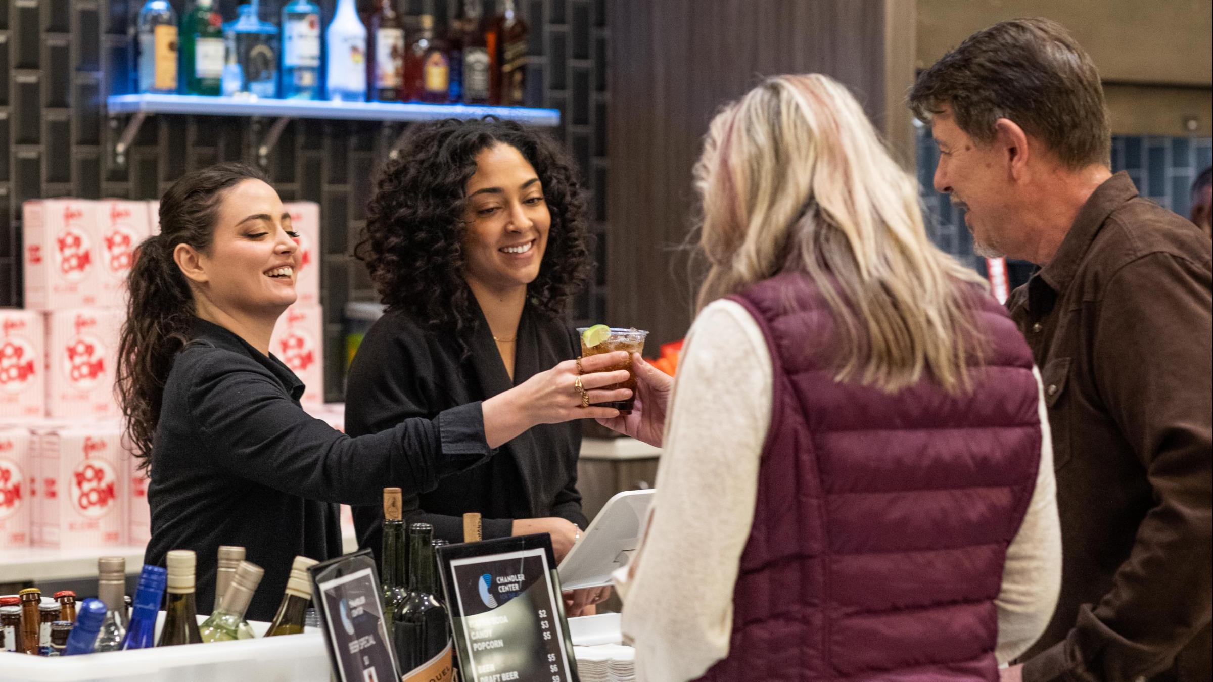 two bartenders serving customers 