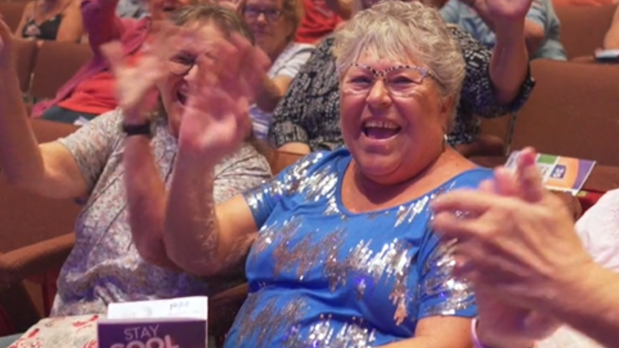 patrons smiling and waving from theatre seats